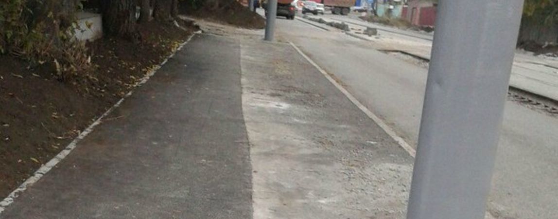 Рабочие расширили тротуар со столбами на Комсомольской